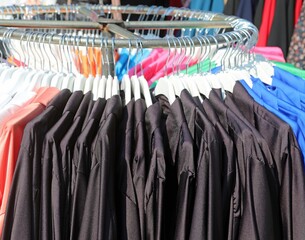 black clothes and aprons for kindergarten and elementary school hanging on the coat rack in a trendy clothing stall