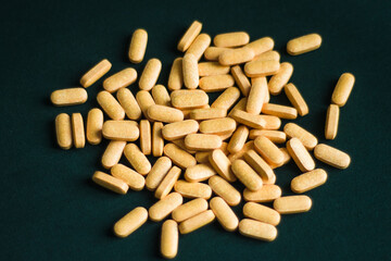 yellow oblong tablets are scattered over  dark green background
