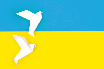 Two white origami paper doves on colors of flag of Ukraine. The concept of peace between two...
