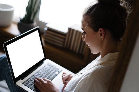Mockup image of a woman using and typing on laptop computer keyboard with blank white desktop screen.