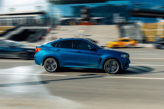 Blue color car BMW X6 F16 xDrive40d in fast motion on the street