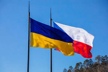 Karlstejn, Czech Republic, 12 March 2022: Flags of Ukraine and Czech Republic or Czechia on flagpoles flying on poles side by side. Independent free Ukraine. Solidarity with Ukraine people.