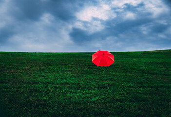 Red Umbrella on Green Hill with Cloudy Blue Sky