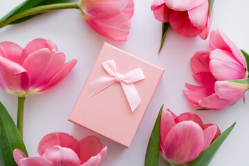 close up view of gift box near bright pink flowers on white.