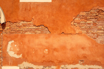 Brick orange wall with old paint cover falling off texture, Murano Venice Italy