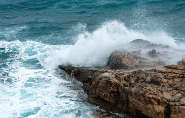 Fototapeta na wymiar Stormy windy waves crashing on the rocks on a rocky coast