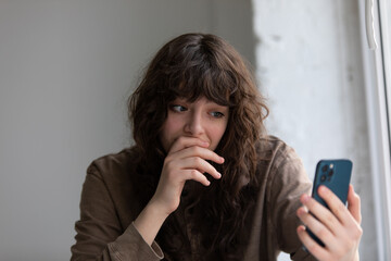 Curly young woman talking on video call using smartphone.