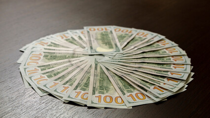 A sheet of new hundred dollar bills are laid out on the table, in a row and in a circle. Great background for filling.