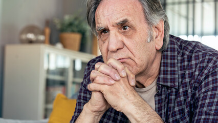 Thoughtful elderly man sitting alone at home	