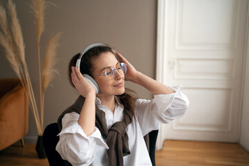 Portrait of a woman with glasses in the office listening to music with headphones break