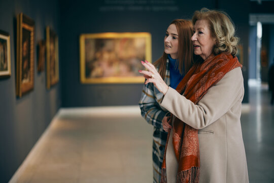 A grandmother and her grandchild enjoying the painting exhibition at gallery.