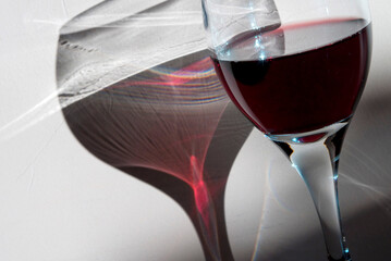 glass of red wine with a reflection on a wall