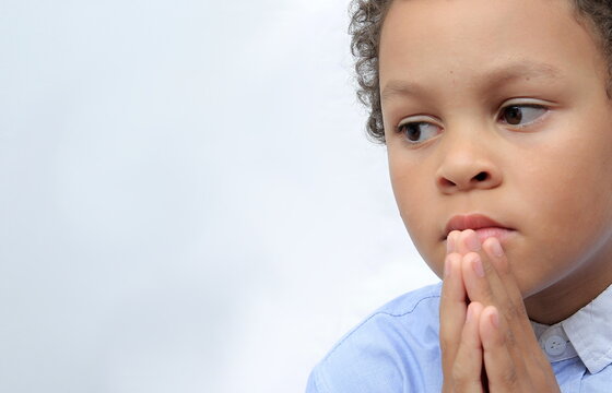 boy praying to God with hands together stock photo