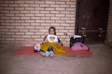 KIEV, UKRAINE - March 24, 2022: The war in Ukraine. a little girl in a bomb shelter holds a drawing...