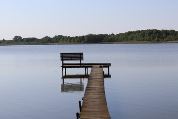 wooden pier with a bench by the lake