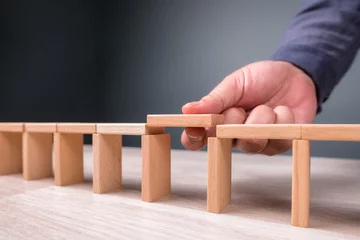 Zelfklevend Fotobehang Hand build a toy bridge by wooden blocks and going to add the final piece between the gap to complete, concept of help solution, solve the disconnect problem © patpitchaya