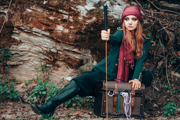 Outdoor portrait of young female in pirate costume holding a sword.