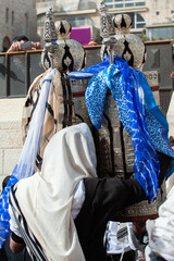 A man lifts a silver case holding a Sefardic-style Torah and shows it to the congregation during...