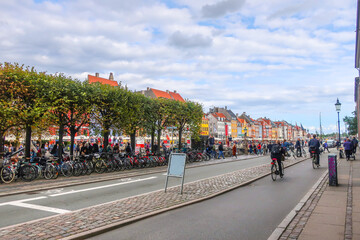 Bicyclists ride past parked bicycles along the Nyhavn Canal in the historic, touristic district of...