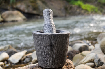 used granite mortar and pestle with fire place as a background. traditional primitive grinder made with stone. best for primitive and traditional background.