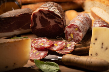 Cutting board with ham, salami, cheese, bread on a rustic wooden board