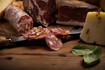 Cutting board with ham, salami, cheese, bread on a rustic wooden board