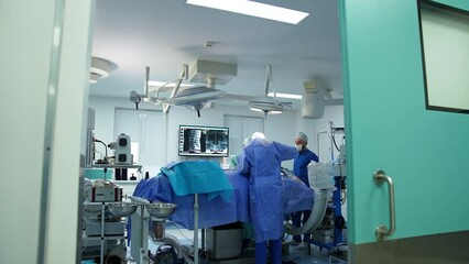 Entering the modern highly-equipped operational theatre in modern hospital. Doctors performing neurosurgical operation using diverse tools.