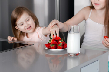 Preteen girl holding raw straberry, eating healthy food, drinking milk
