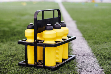 Set of reusable yellow bottles on a soccer field background.