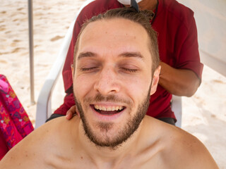 White Man with his Eyes Closed is Enjoying the Head Massage he is Getting at the Beach