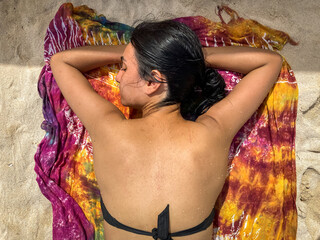Dark-Haired Woman is Lying Sunbathing on a Towel on the Sand