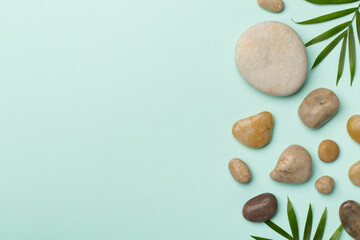 Spa stones and leaves on color background, top view