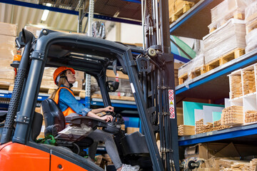 Young female forklift driver working in a warehouse
