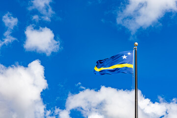 Curacao flag waving against a beautiful blue sky with white clouds