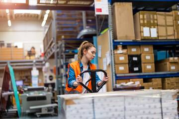 Young worker moving goods on pallet jack at warehouse