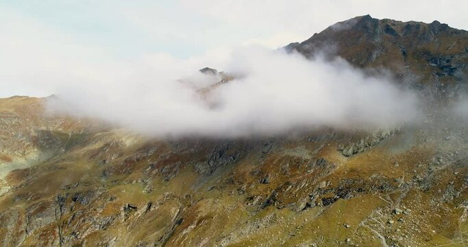top of the ridge of a rocky mountain in the cloud. mountains with green mog through the clouds. drone view