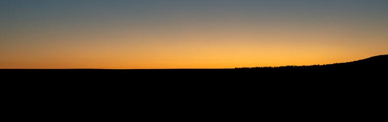 Sunset and hills in silhouette (banner).