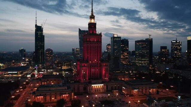 Red illuminated monumental high rise Palace of Culture and Science and downtown skyscrapers at twilight time. Warsaw, Poland
