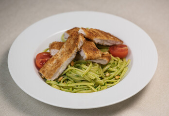 Turkey cutlet and Green spinach spaghetti with cheese and tomato on wooden table