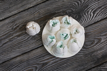 Homemade marshmallows of different shapes and colors. Zephyr flowers. On pine boards.