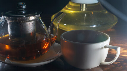 Picture of glass teapot with ceramic cup of green tea on dark background. Hot chinese green tea.