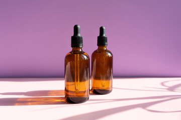 
Cosmetics package branding mockup still life amber, dropper, black bottle dispenser, packaging and branding items. Blank, isolated on a powdery pink-lilac background, to place your design.
