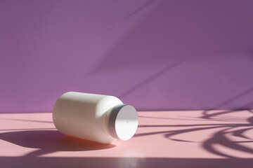 
white cosmetic jars on a lilac-pink background with sun shadows. template for cosmetics. still life for a cosmetic article.