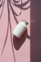 
white cosmetic jars on a lilac-pink background with sun shadows. template for cosmetics. still life for a cosmetic article.