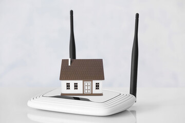 Modern wi-fi router on table near white wall