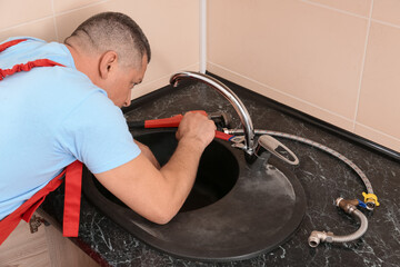 Plumber repairing sink in kitchen