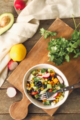 Composition with bowl of Mexican vegetable salad and ingredients on wooden background
