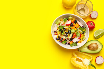 Fototapeta na wymiar Bowl of Mexican vegetable salad with black beans, radish and ingredients on yellow background