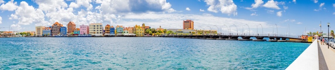 Fototapeta premium Famous colorful waterfront buildings in dutch-caribbean, colonial style and Queen-Emma-Bridge viewed from the district Otrobanda in Willemstad, Curacao
