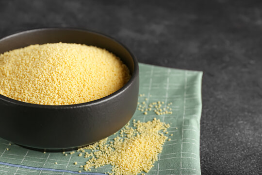 Bowl of raw couscous on dark background